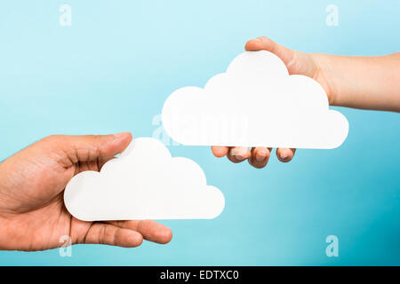 Two hands holding paper clouds on blue background. Cloud computing concept. Stock Photo