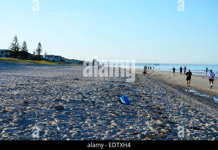 Early morning joggers and people exercising on beautiful wide open sandy beach with calm ocean. Taken at 7 am in South Australia Stock Photo