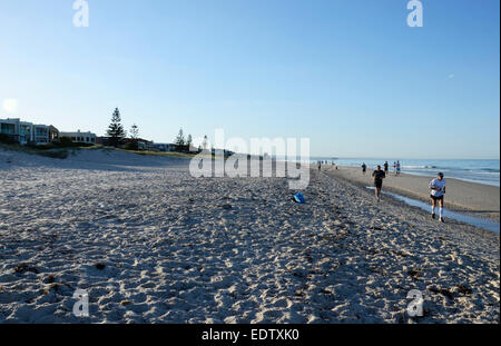 Early morning joggers and people exercising on beautiful wide open sandy beach with calm ocean. Taken at 7 am in South Australia Stock Photo