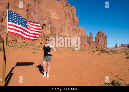 Female tourist poses by an American flag in Monument Valley Stock Photo