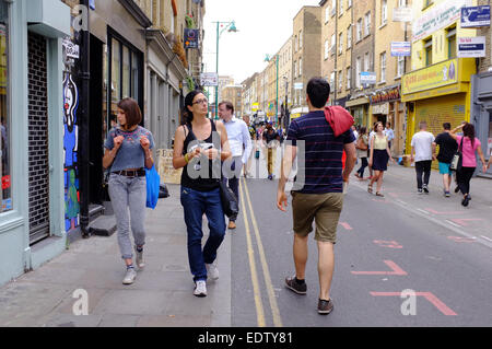 young people walking past closed shops on Sunday in Brick Lane, Shoreditch, London Stock Photo