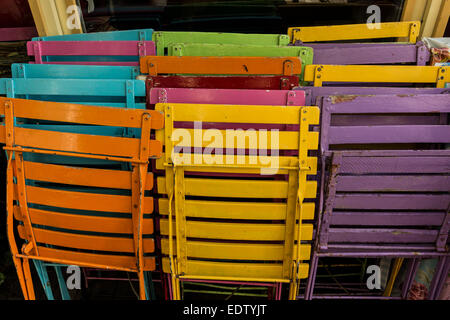 A restaurant stacks colorful chairs to set up for outdoor seating on a sunny day in the Netherlands Stock Photo