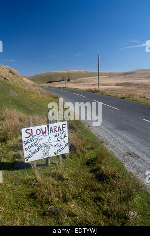 Araf Slow Sheep Dogs and Shepherds Defaid Cwn a Bugeiliad humorous cartoon style hand painted unofficial road sign on Cwmystwyth Stock Photo