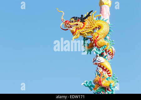 The old statue of gold dragon bind pillar and blue sky Stock Photo