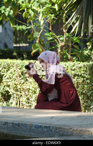 Seville Spain: Young woman taking photograph inside the Alcazar gardens Stock Photo