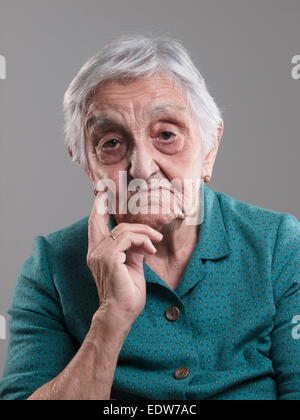 Elderly woman portrait in a studio shot. Old woman had her hand on chin and sad Stock Photo