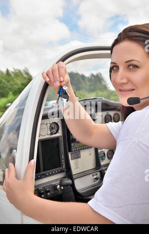 Pilot girl sitting in the cockpit and showing keys Stock Photo