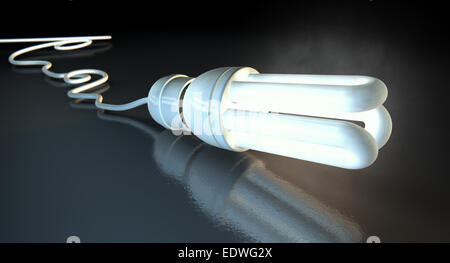 An illuminated fluorescent light bulb connected to an electical cable laying on a dark surface with a dramatic spotlit backgroun Stock Photo