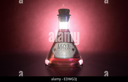 A regular old goblet glass bottle filled with a pink liquid with a label showing it is love potion and sealed with a cork on a s Stock Photo