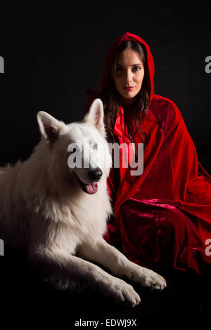 Woman wearing a red hood posing in studio with her dog Stock Photo