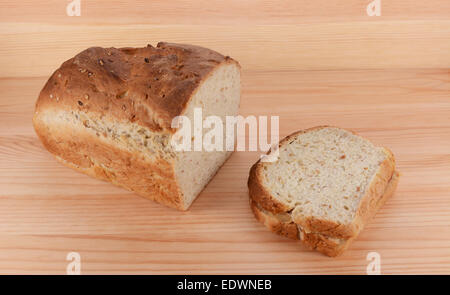 Cut loaf of freshly baked bread with a peanut butter and jelly sandwich on a wooden table Stock Photo