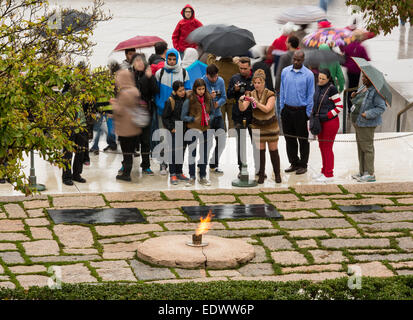 Tourists in the rain taking photos at the eternal flame memorial to President John F Kennedy in Arlington Cemetery near Washingt Stock Photo