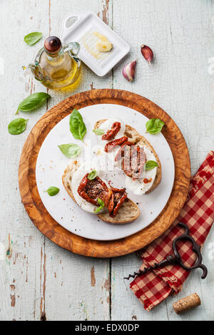 Bread Ciabatta with Mozzarella and Sun dried tomatoes on blue wooden background Stock Photo