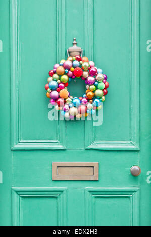 A colorful christmas wreath on a green front door Stock Photo