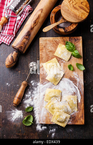 Raw Homemade Ravioli with pasta cutter on dark wooden background Stock Photo