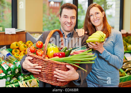 Happy couple buying fresh fruits and vegetables in organic food store Stock Photo