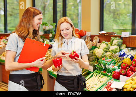 Salesclerk in training getting help from staff in a supermarket Stock Photo