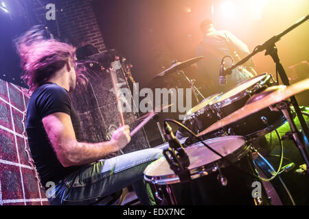 Drummer playing on drum set on stage. Warning - Focus on the drum, authentic shooting with high iso in challenging lighting cond Stock Photo