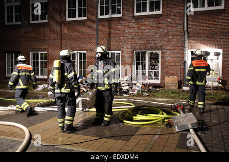 Hamburg, Germany. 11th Jan, 2015. Firefighters stand next to burned files and newspaper issues in the backyard of the 'Hamburger Morgenpost' in Hamburg, Germany, 11 January 2015. An arson attack was commited in the night to sunday. According to police information, people yet unknown threw stones and an incendiary device into the newspaper's archive. German State Security investigates. After the terror attack in Paris, the 'Morgenpost' reprinted 'Mohammed' caricatures of the satirical magazine 'Charlie Hebdo'. PHOTO: BODO MARKS/dpa/Alamy Live News Stock Photo