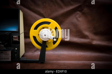 A vintage 8mm movie editing desktop with editing machine part and yellow reel on colored background Stock Photo