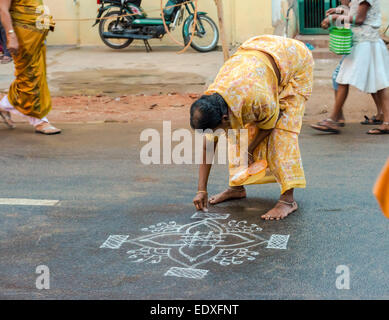 THANJAVOUR, INDIA - FEBRUARY 14: An unidentified woman paints ornaments rice flour on the asphalt road. India, Tamil Nadu, Thanj Stock Photo