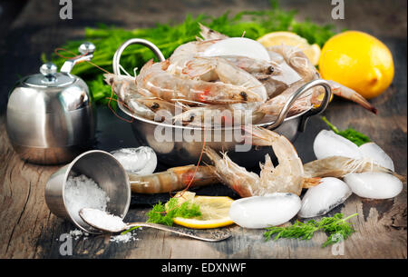 Raw Shrimps on ice with fresh dill and lemon Stock Photo