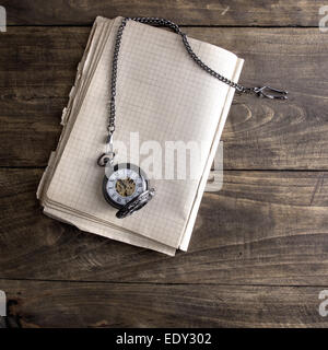 Antique book and pocket watch on grunge wooden table, from above Stock Photo