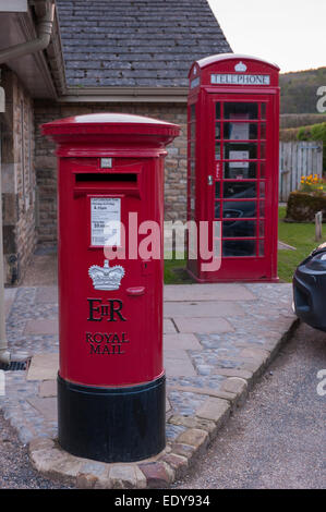 Close-up of 2 British icons - traditional post box & bright red telephone box or kiosk, amenities in Bolton Abbey village, North Yorkshire, England. Stock Photo