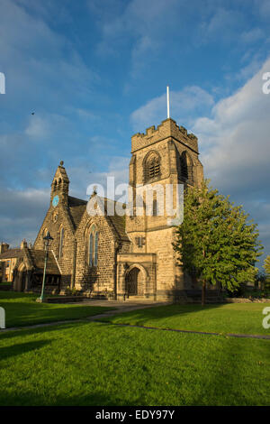 Exterior of St John’s Church (with tall bell tower, porch & clock) sunlit & set against a bright blue sky - Baildon, West Yorkshire, England, UK. Stock Photo