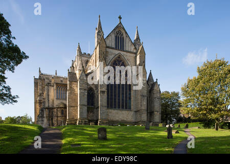 A low-angle view of the east facade of beautiful, towering, historic, sunlit Ripon Cathedral under a bright blue sky - North Yorkshire, England, UK. Stock Photo