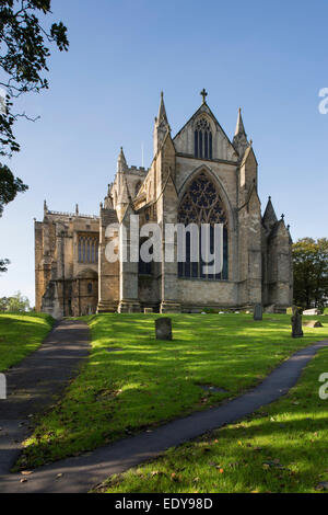 A low-angle view of the east facade of beautiful, towering, historic, sunlit Ripon Cathedral under a bright blue sky - North Yorkshire, England, UK. Stock Photo