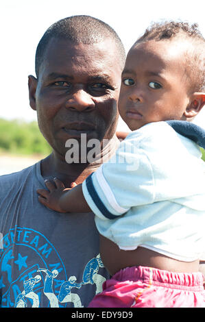 Happy dad carries serious podgy cute son. Stock Photo