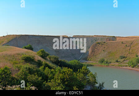 A dug out lake surrounded by sandstone cliffs and shrubbery Stock Photo