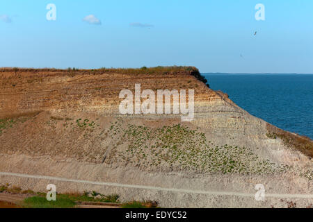 A sandstone cliff protrudes into the sea under a blue sky Stock Photo