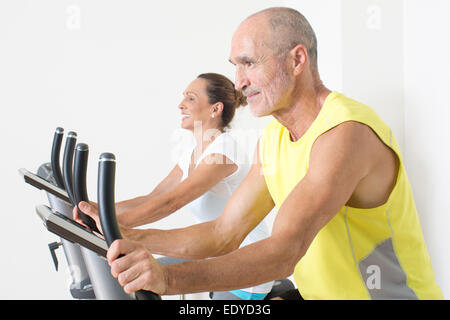 Elderly couple having fun while cycling in gym Stock Photo