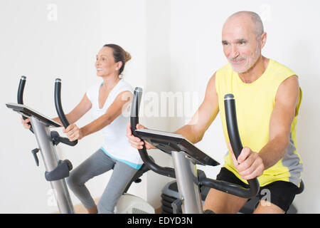 Elderly couple having fun while cycling in gym Stock Photo