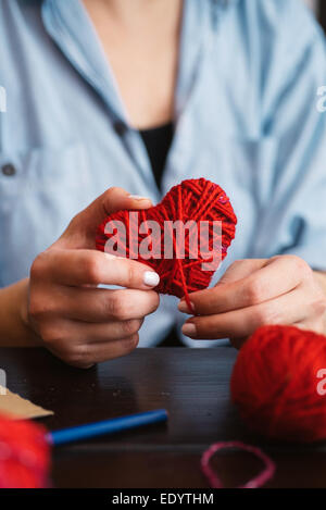Woman creating red woolen heart Stock Photo