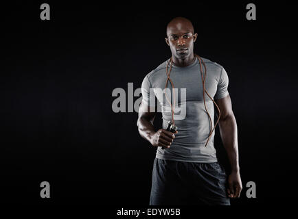 Studio shot of young African muscular man with jumping rope against black background. Fitness model with skipping rope. Stock Photo