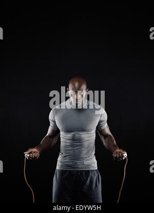 Studio shot of masculine African man skipping rope with copy space. Portrait of muscular young man exercising with jumping rope. Stock Photo