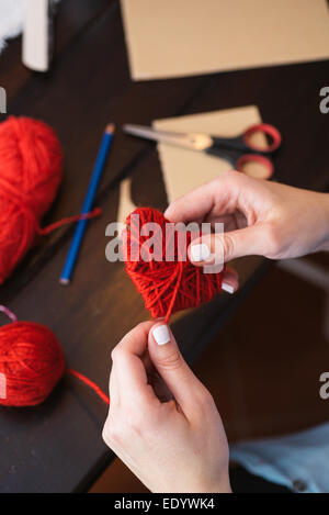 Woman creating red woolen heart Stock Photo