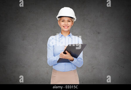 smiling businesswoman in helmet with clipboard Stock Photo