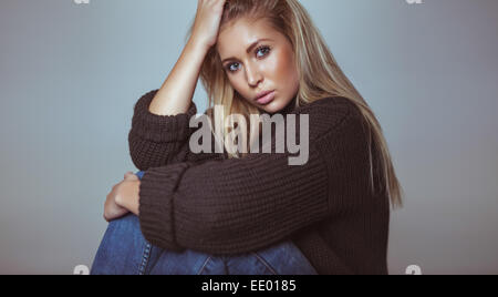 Portrait of beautiful blond female in sweater looking at camera. Pretty young woman in studio. Stock Photo