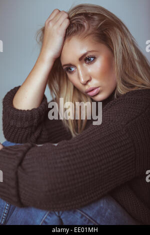 Thoughtful young woman in sweater looking away. Pretty young woman. Stock Photo