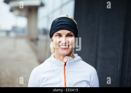 Portrait of cheerful young fitness woman. Smiling young female athlete in sports wear outdoors. Stock Photo