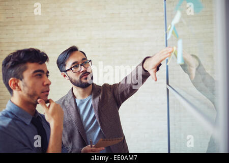 Asian businessman explaining point of working plan to colleague Stock Photo