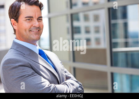 Successful businessman or business man arms folded in a suit in a modern city Stock Photo