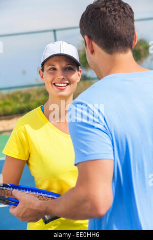 Rear view of young man and woman couple playing tennis or having tennis lesson Stock Photo