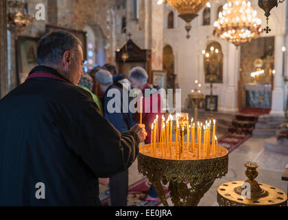 Man lighting a candle in a Greek Orthodox church. In the village of Exohori, Outer Man, Peloponnese, Greece. Stock Photo