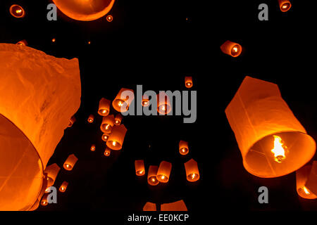 Lighted paper lanterns float skyward into the dark night as part of the Buddhist Yee Peng International Festival in Chiang Mai. Stock Photo