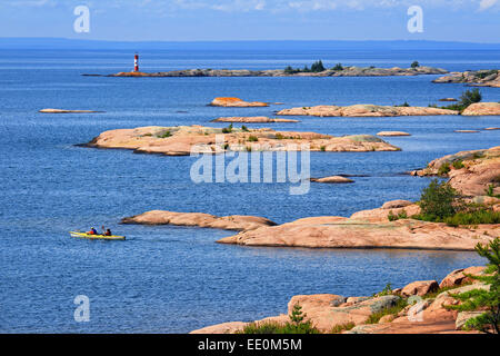 Rocky shoreline in Killarney Provincial Park with people in kayak. Stock Photo